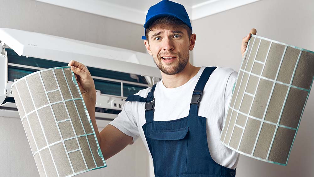 Change your AC filters in time. man showing dirty filters taken out from an air conditioner.