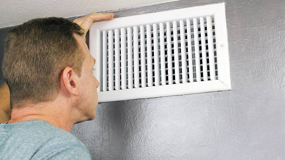 A man checking airflow through air vents