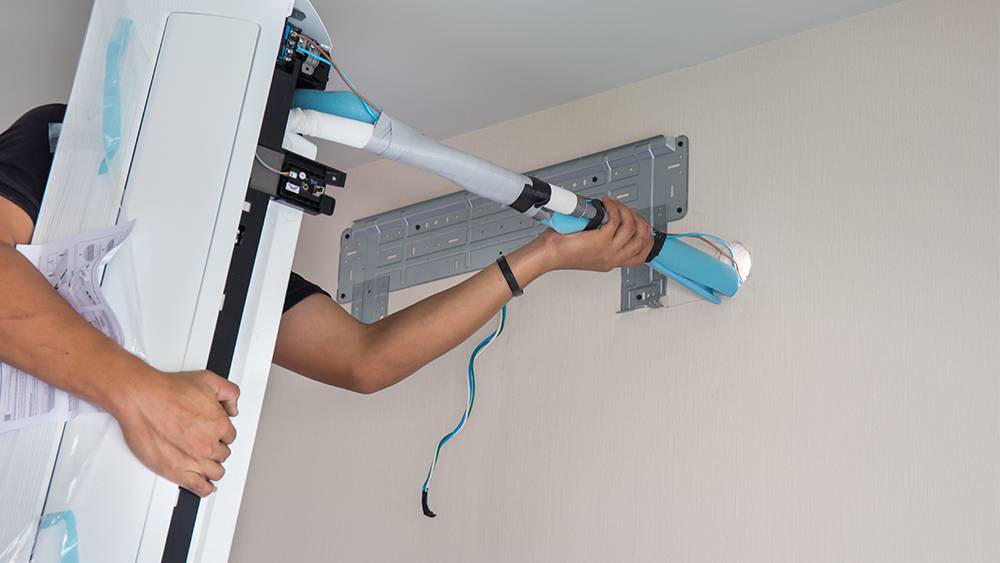 An HVAC techician mounting the mini-split for installation