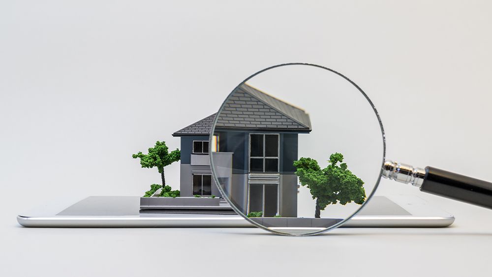 miniatuur huismodel met vergrootglas 
