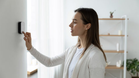 A woman using smart thermostat