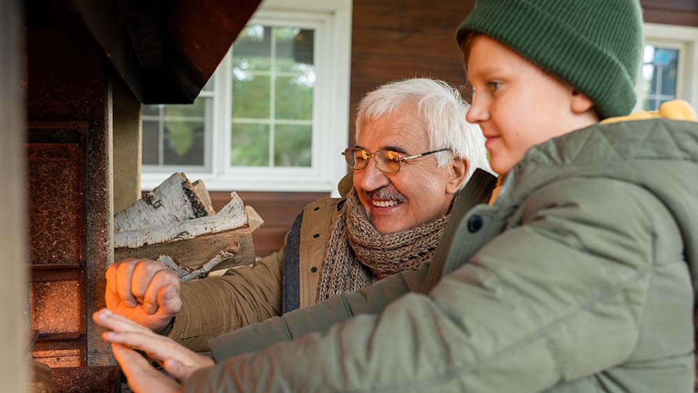 An elderly man and his grandson warming their hands in front of a DIY heater