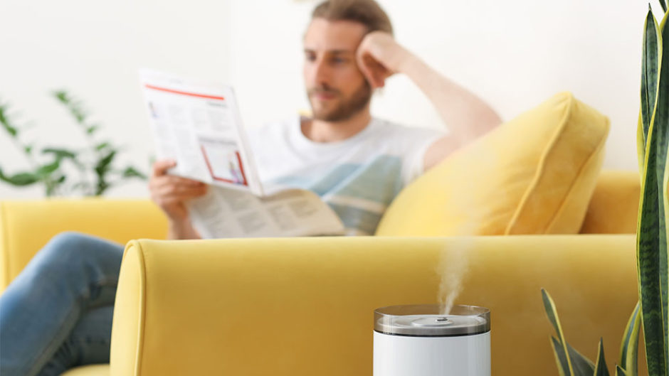 Man reading magazine. A humidifier is placed nearby